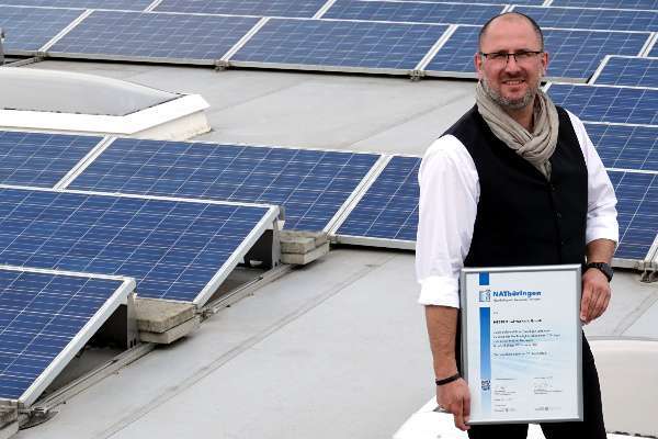 Geschäftsführer Robert Nettelnstroth mit der Aufnahmeurkunde auf dem mit Photovoltaikmodulen bestückten Dach des Werkes in Schkölen